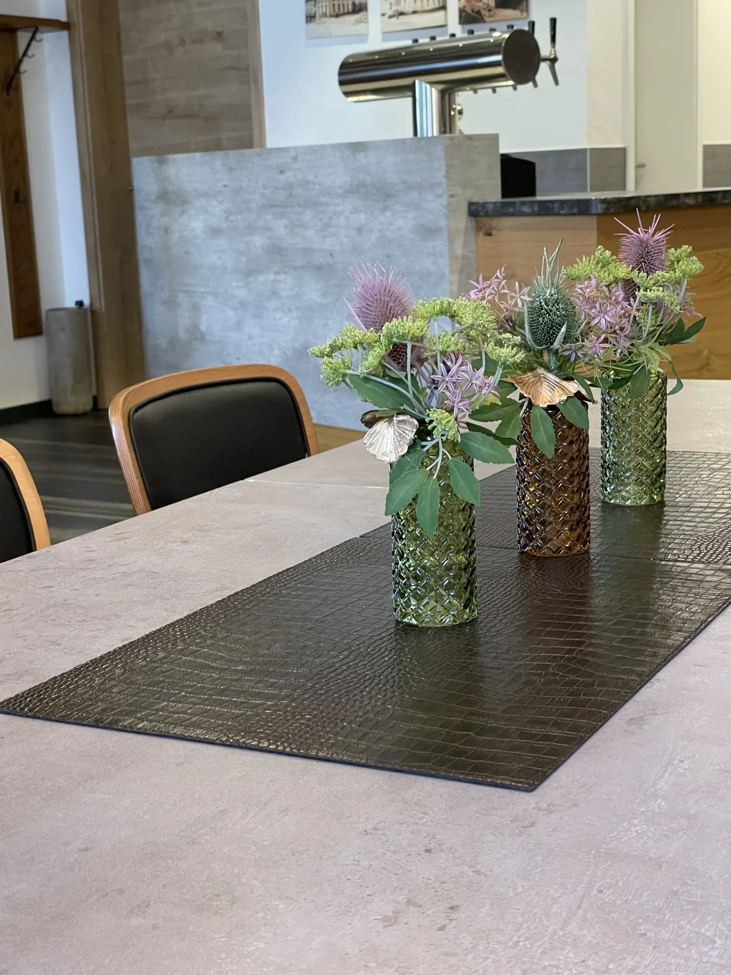 Drei Glasvasen mit Blumen auf einem gedeckten Tisch im Gasthof Adler