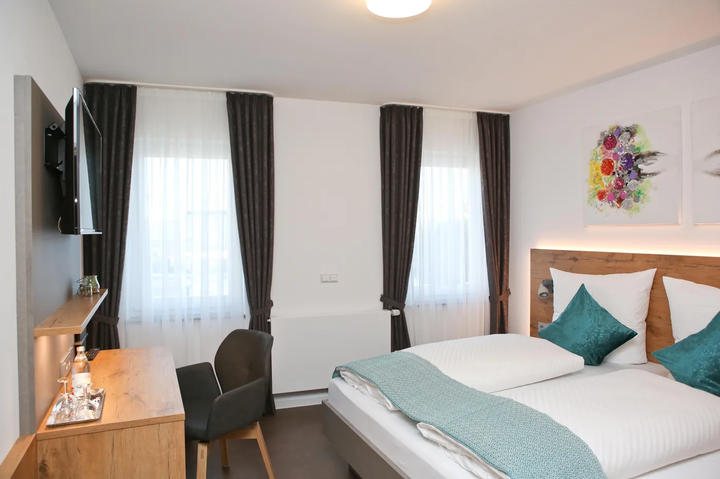 Doppelzimmer im Adler mit türkisen Kissen, Holzkopfteil und zwei Fenstern
